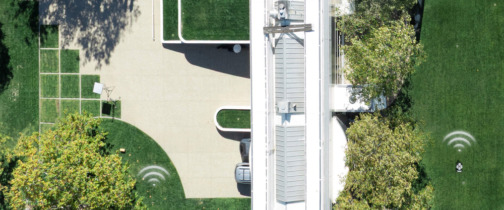 Navimow i105E robotmaaier maait het gras bij een wit gebouw.